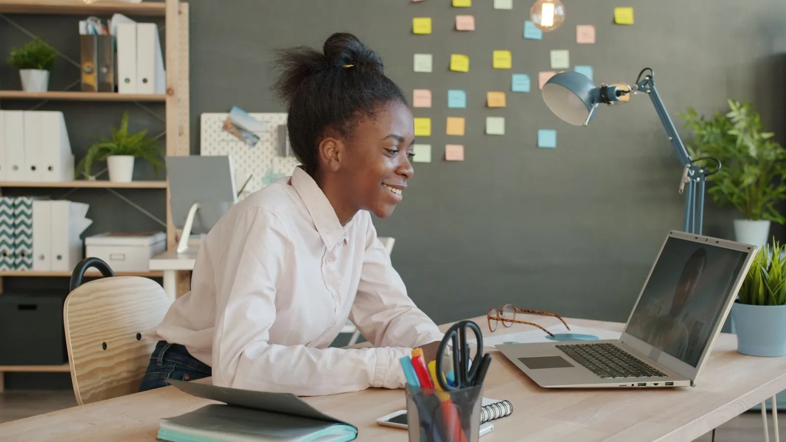 Focused young woman on video call in modern office setting.